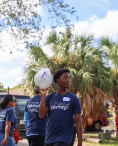 Student carrying a turkey Love Serves Feed The Block HomesUnited Ministries (3)