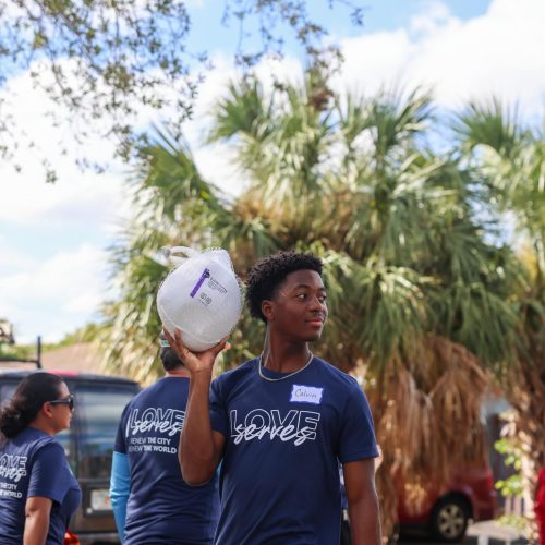 Student carrying a turkey Love Serves Feed The Block HomesUnited Ministries (3)